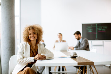 Young businesswoman using digital tablet in the office with young people works behind her