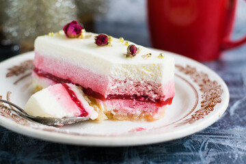 Delicious mousse cakes on white substrates, red cup with tea or coffee and christmas decor on gray background