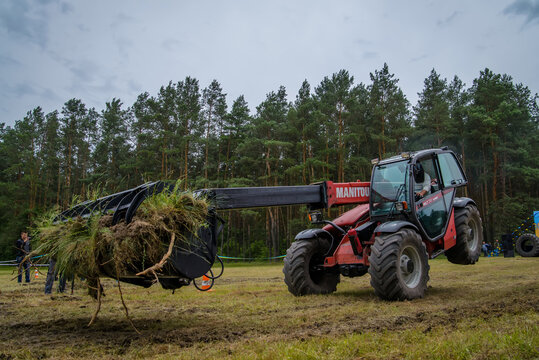 Cherkasy, Ukraine - June 16, 2015: Work on red tractor loader Manitou performs tricks. Riding on the front wheels.