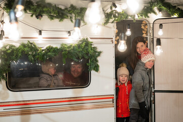 Happy large family celebrates christmas in nature. Parents with three sons travels in a mobile home. 