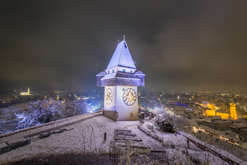 The snowy Uhrturm at the Schoßberg hill in the middle of Graz in a snowy and cold winter night
