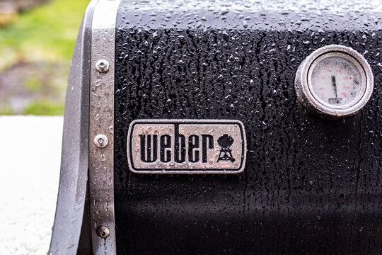 Hillsboro, Oregon  USA - 24 May 2020: Up close photo of a logo of Weber company on top of a gas grill covered in raindrops