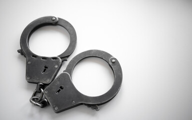 Metal handcuffs of a policeman on a white isolate. A clean place for text. Arrest of the suspect. criminal news.