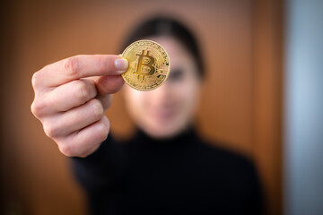 Young woman show golden bitcoin close to camera