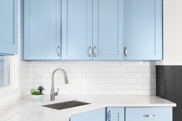 Detail of a kitchen with light blue cabinets, white granite countertop, subway tile backsplash, and...