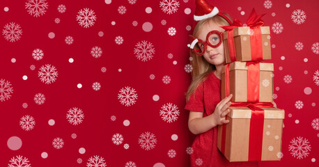 happy girl with christmas gifts on red background with snowflakes and copy space