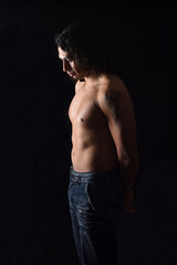 Fototapeta na wymiar low key portrait of a man looking down with tattoos on black background
