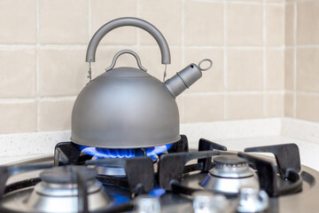 A metal kettle on a burning gas stove, shallow depth of field.
