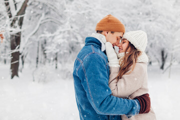 Valentine's day. Young loving couple walking in winter park. Man and woman hugging enjoying snowy landscape outdoors