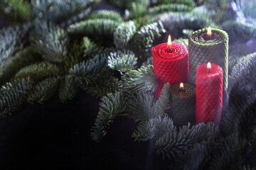 Red and green holiday wax candles with fir branches. Nobilis branch. Smoke from candles. The...