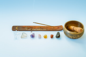 Burning incense stick and 7 chakra crystals  with tibetan sound bowl on white background	