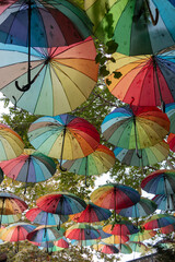 Colorful umbrellas outside as decor. Umbrellas of different colors against the sky and the sun.