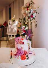 White wedding cake with pink and white flowers of peonies and roses.