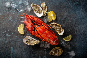 Boiled cooked red whole lobster ready to eat and fresh open oysters served with lemon wedges and ice cubes top view flat lay on blue concrete stone background, seafood plate  