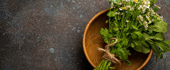 Bunch bouquet of fresh wild flowers and healing herbs in rustic wooden bowl top view flat lay on...