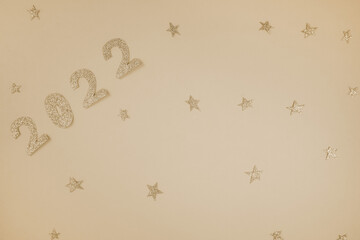 Happy New Year 2022. Christmas background with golden glittering numbers 2022 on starry light sandy...