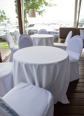 interior with white tables and chairs in a cafe restaurant under white tablecloths