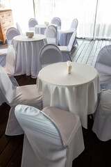 interior with white tables and chairs in a cafe restaurant under white tablecloths