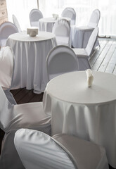 interior with white tables and chairs in a cafe restaurant under white tablecloths
