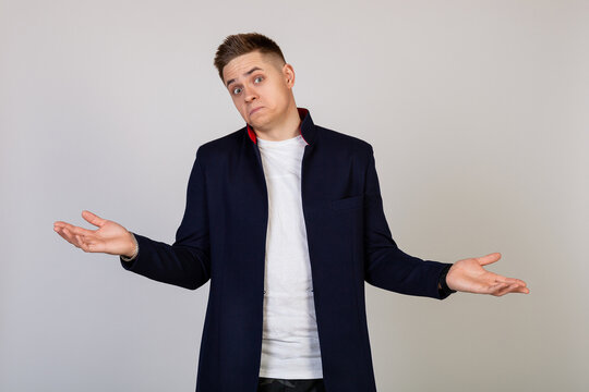 Male young man with a lost expression shrugs his shoulders. The guy spreads his hands and does not know what to say in response