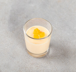 Tangerine Panna Cotta in a glass on a light gray background