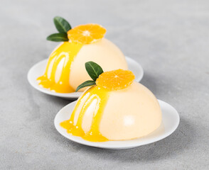 Tangerine pudding, Panna Cotta with sauce on a platte on a light gray background