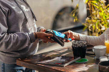 Fototapeta premium Side view of a couple paying bill at coffee shop using credit card payment
