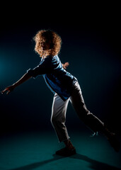 Young dance artist perform acrobat moves isolated on dark background