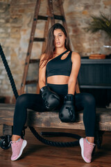 Obraz na płótnie Canvas Beautiful young fitness girl posing at camera in black boxing glove