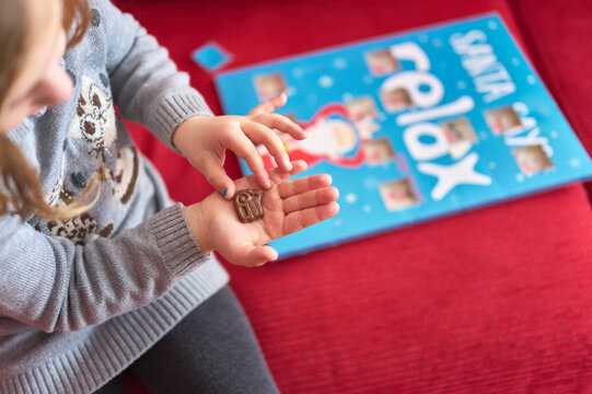 girl eating a chocolate from an advent calendar at christmas tim