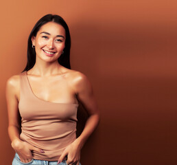 Fototapeta na wymiar young pretty asian woman cheerful smiling posing on warm brown background, lifestyle people concept