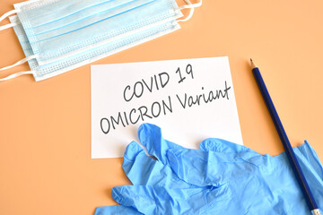 Covid-19 new Omicron variant. Medical face masks, blue medical gloves and pencil with white paper and text 