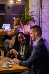 Two business people having a meeting in a cafe while using a laptop