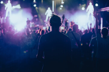 Silhouette of a man in front of bright stage lights on a music festival