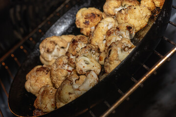 Cooking, fried cauliflower with herbs and spices. Vegetarian food, healthy food baked in the oven. Selective focus. Low key. Sloping, shifted horizon