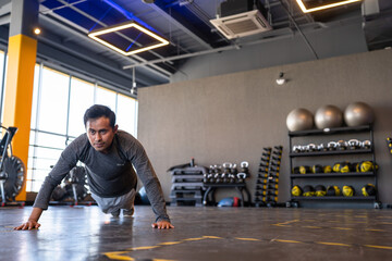 Fototapeta premium Portrait of a fitness person doing push ups in gym