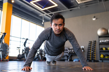 Fototapeta na wymiar Portrait of a fitness person doing push ups in gym