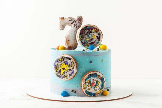 Kyiv, Ukraine - September 04, 2021: Birthday cake for a boy with blue cream cheese frosting decorated with gingerbread cookies in the shape of spinning top of popular game Beyblade