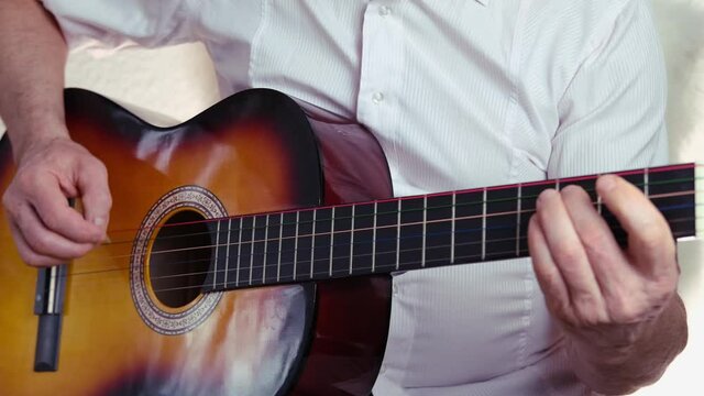 closeup male hands, middle-aged man plays acoustic guitar music, teacher teaches how to play musical instrument, blogger performance, concept of unique bard song