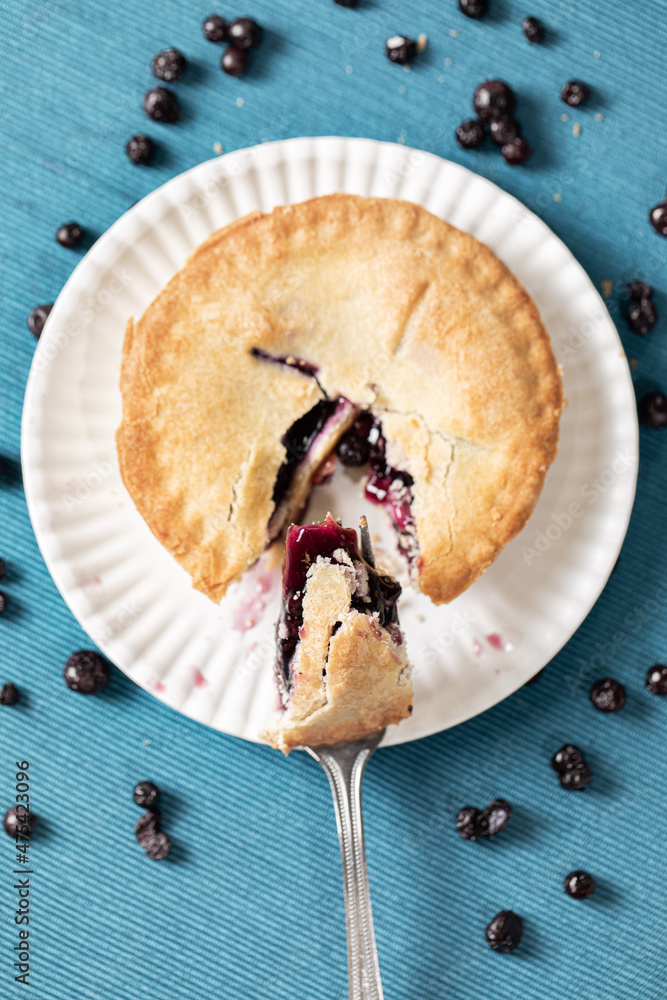 Poster vertical top view of a blueberry pie with a fork taking a slice out