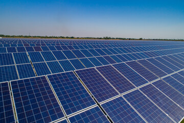 Solar power plant, solar panels shot from a drone, blue sky and clouds