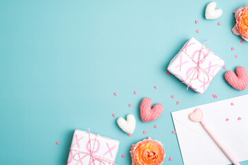 Happy Valentines Day composition. Flat lay gift boxes, knitted hearts, pen, paper on pastel blue background.