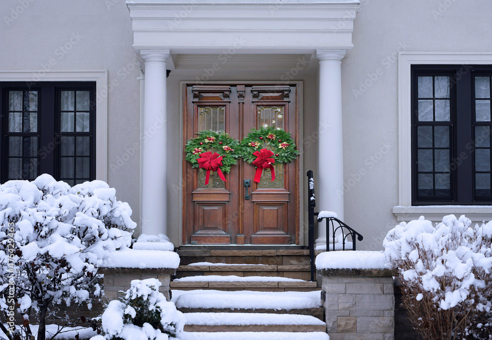 Poster house in winter with elegant wood grain double front door with christmas decorations