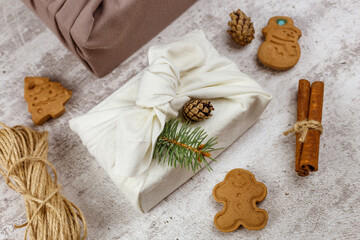 Christmas eco friendly gift wrapping in traditional Japanese Furoshiki style. Environmental present wrapping concept. Presents with green fir, pine cones, cinnamon and Gingerbread cookies.