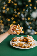 Ginger Christmas cookies in children's hands on the background of the Christmas tree.