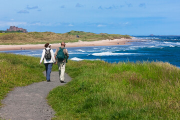 Tourists hiking along the coast of Northumberland, England, UK - obrazy, fototapety, plakaty