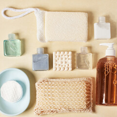 Personal care items. Shampoo, conditioner, bath sponges, moisturizer, aromatic white body soap, scourer, peach colored hand soap, on a pastel yellow background.