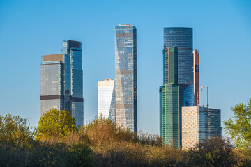 Green trees on background modern skyscrapers in the Moscow city. Panorama of new Moscow City buildings in spring