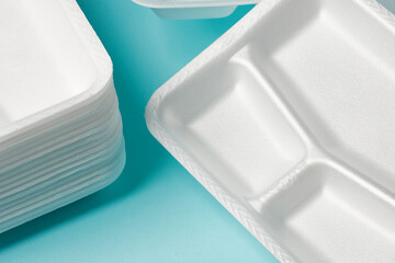 white Styrofoam plastic plates on blue background. Trash plastic, reusable plastic, disposable, for...