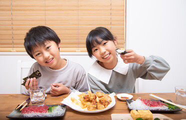 Obraz na płótnie Canvas 家で晩御飯を食べる小学生の男の子と女の子